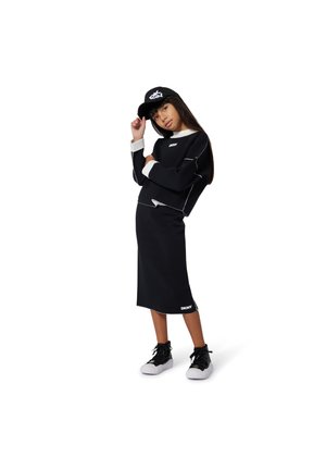 Zwart sportoutfit bestaande uit een cropped sweatshirt en een knielange rok, met witte accenten en merklogo. Zwarte sneakers maken de look compleet.