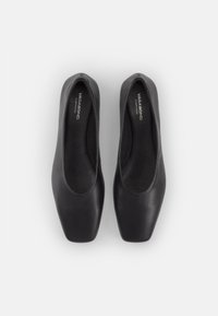 Paire de chaussures plates en cuir noir avec bouts carrés, vues de dessus sur un fond clair uni.