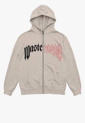 Beige Kapuzenpullover mit Reißverschluss, vorderen Taschen, schwarzem Gothic-Text "waste" auf der linken Brust und rotem, tropfendem, stilisiertem Grafikdruck auf der rechten Brust.