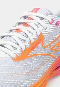 Grå atletisk sko med struktureret mesh-overdel, hvide snørebånd, orange accenter og pink detaljer. Har "WAVE RIDER 29" branding.