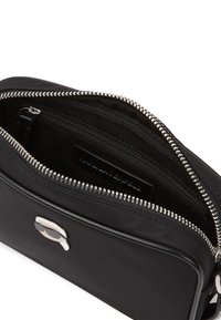 Black nylon zippered bag with silver hardware, two inner compartments, and a fabric lining featuring a subtle pattern.
