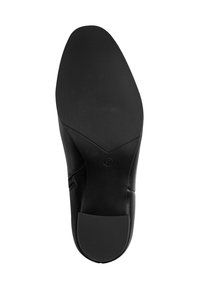Suola di scarpa in pelle nera con superficie testurizzata, caratterizzata da una punta liscia e un tacco pronunciato. Leggero marchio impresso vicino all'area dell'arco.