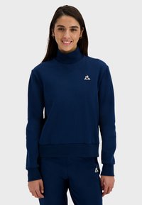 Navy blue sweatshirt with a high collar, ribbed cuffs, and hem; features a small embroidered logo on the chest; smooth texture.
