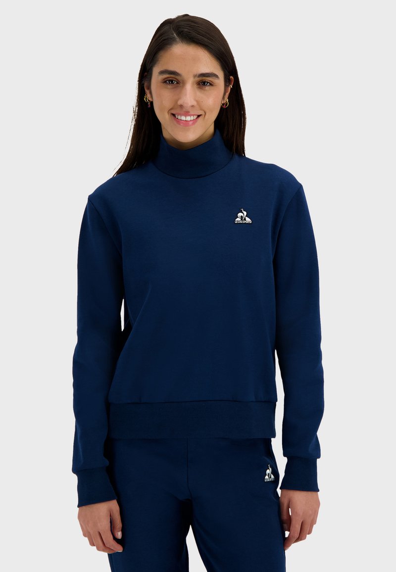 Navy blue sweatshirt with a high collar, ribbed cuffs, and hem; features a small embroidered logo on the chest; smooth texture.