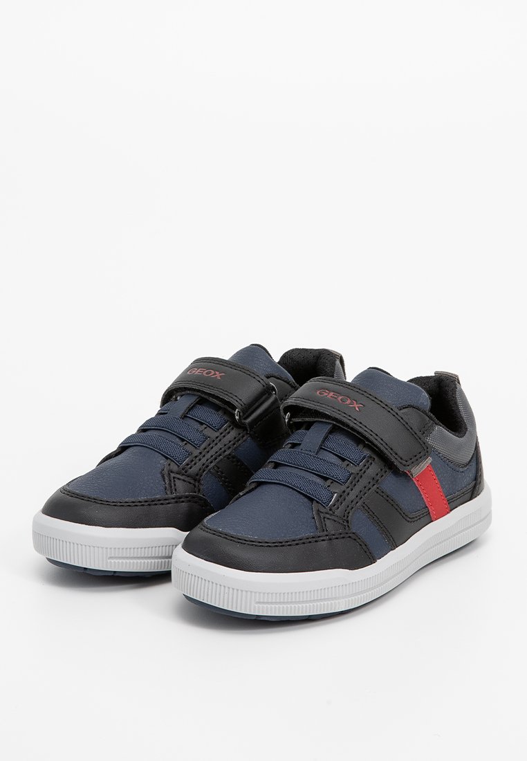 Chaussures synthétiques bleu marine et noires avec des accents rouges, dotées d'une sangle auto-agrippante et d'un laçage, semelle en caoutchouc texturée et bout arrondi.