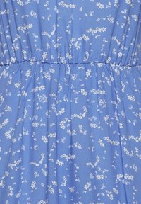 Light blue fabric with a floral pattern in white. The texture is smooth with an elastic waistband creating subtle gathers.