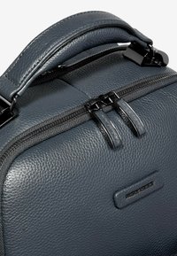 Borsa in pelle grigia con superficie testurizzata, doppio cursore con cerniera e design elegante con un sottile accento logo.