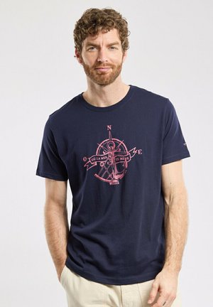 Navy cotton t-shirt featuring a compass design in pink with the text "Où la mer te mène." Short sleeves and round neckline.