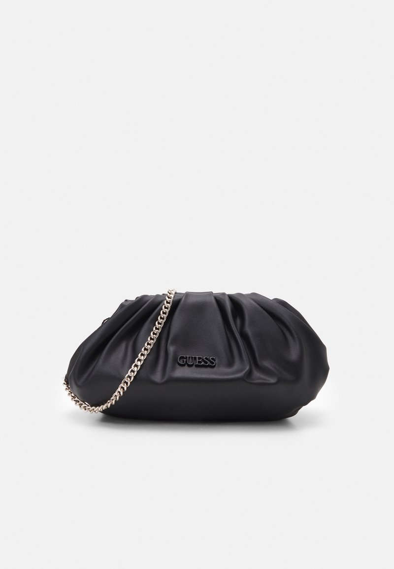 Pochette en cuir souple noir avec bandoulière chaîne argentée et logo "GUESS" embossé sur le devant, sur fond blanc uni.