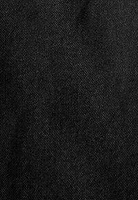 Tejido de denim negro que muestra un fino entramado diagonal. La textura es suave con ligeras variaciones, mostrando un leve desvanecimiento en algunas zonas.