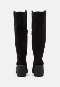 Botas negras de ante hasta la rodilla con tacón de bloque, que cuentan con dos cremalleras laterales y una textura suave.