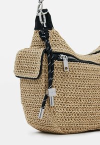 Borsa di paglia intrecciata in beige con dettagli in pelle nera, dotata di un scomparto con zip, cordino decorativo a nodo e dettagli in metallo.
