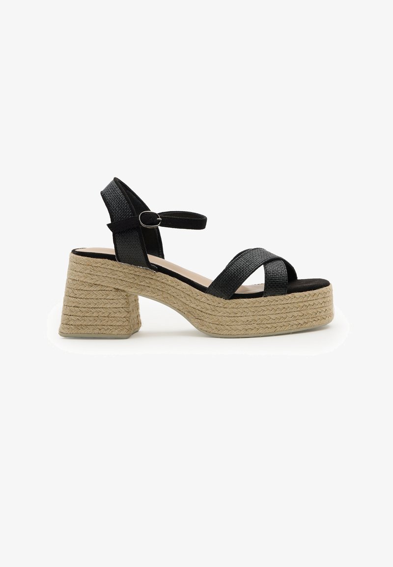Sandalia negra de tiras trenzadas con hebilla en el tobillo, plataforma y tacón ancho envueltos en material de yute trenzado.
