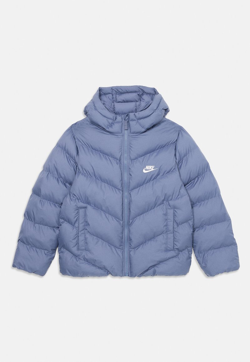 Pufasta plava jakna s kapuljačom, s chevron šavovima, prednjim patentnim zatvaračem i bijelim Nike logom na lijevoj strani prsiju. Glatka tekstura.