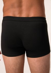 Boxers negros ajustados, fabricados con una tela suave, que cuentan con una cinturilla elástica blanda y un diseño ceñido. Estilo minimalista.