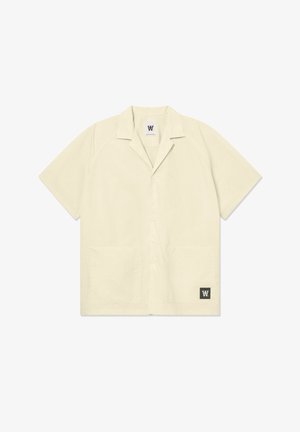 Lühikeste käistega, heledast beežist riidest särk, mis on valmistatud pehmest kangast. Omab laia krae, esipoolt nuppe ja kaht esist pocketit. Logo alumises nurgas.