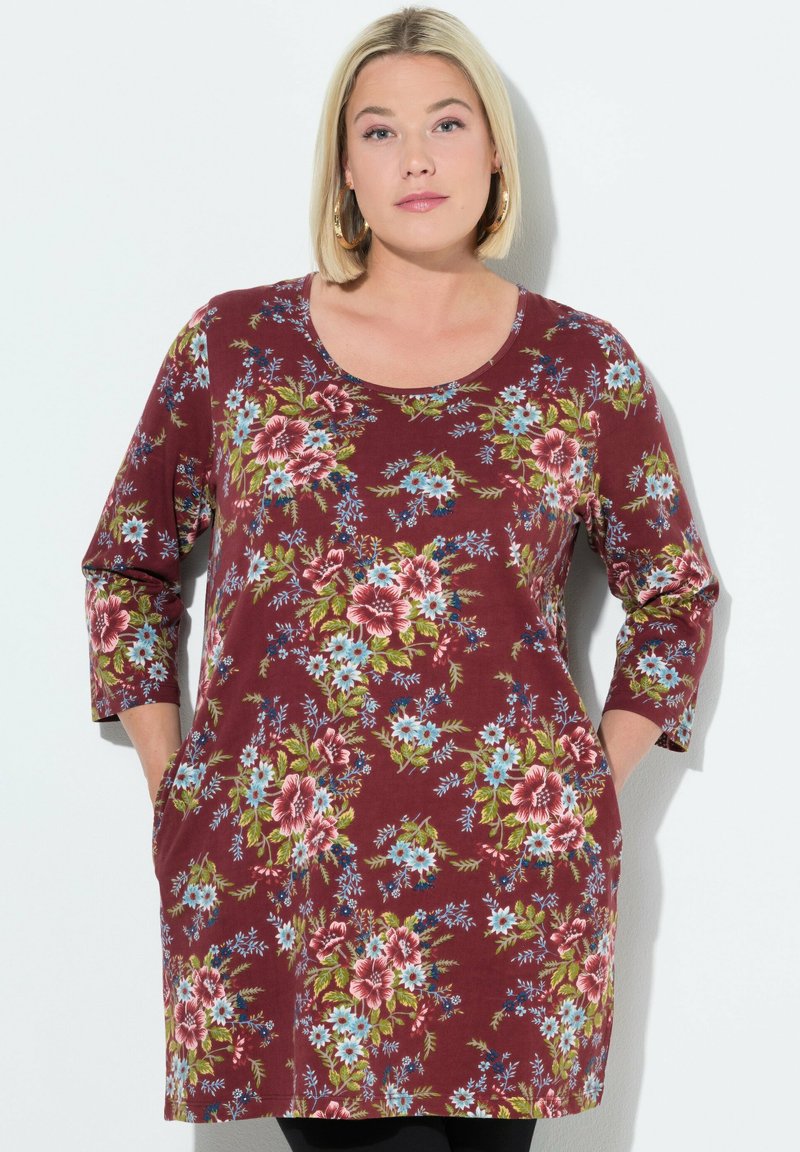 Bordeauxfarbene Blusentunika mit drei Viertelärmeln, die blaue und rosa Blumen zeigt, runder Ausschnitt und Seitentaschen hat. Aus weichem, leichtem Stoff.