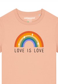 Perzikkleurige katoenen t-shirt met een kleurraf rainbow graphic met sterren erboven en de tekst "LOVE IS LOVE" eronder in vetgedrukte zwarte letters.