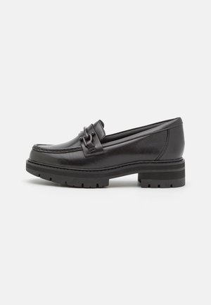 Zwarte leren loafer met dikke profielzool en decoratieve band aan de zijkanten, getoond in profiel tegen een witte achtergrond.