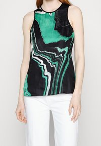 Top negro sin mangas con patrón marmoleado en verde y blanco, con escote redondo y textura suave. Combinado con pantalones blancos.