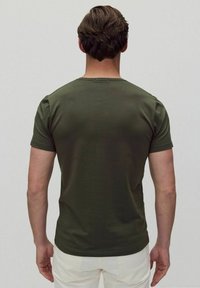 Oliven grøn kortærmet t-shirt med rund hals; glat tekstur og tætsiddende design, set fra ryggen mod en neutral baggrund.