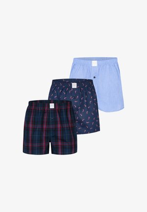 Drie paar katoenen boxershorts voor jongens: één blauw, één donkerblauw met een zuurstokpatroon en één geruit met rode, groene en blauwe strepen.