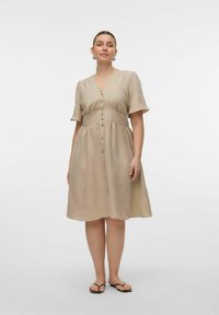 Robe boutonnée, longueur genou, en beige clair avec des manches courtes et une taille cintrée. Tissu texturé avec un léger lustre et boutons naturels.