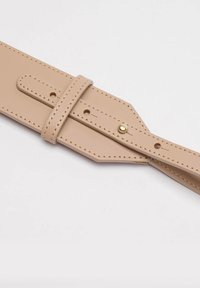 Beżowy skórzany pasek z detalami w postaci szwów, regulowany za pomocą otworów, z akcentem w postaci złotego ćwieka z jednej strony. Płaski, wydłużony kształt.