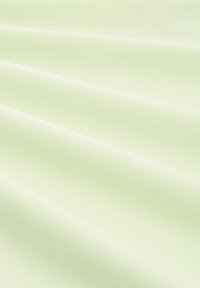 Lichtgroene stof met een gladde textuur, gekenmerkt door zachte plooien en kreukels, die een uniforme kleur en matte afwerking toont.