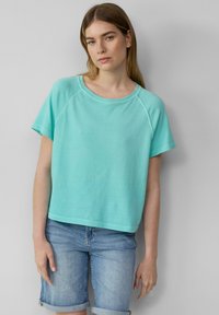 Turquoise katoenen t-shirt met een ronde hals en korte raglanmouwen, gecombineerd met opgerolde denim shorts. Glad oppervlak, casual pasvorm.