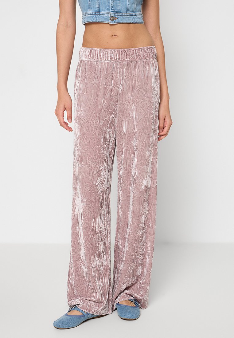 Jasnoróżowe, szerokie spodnie z wrinklowanej, teksturowanej tkaniny z elastycznym pasem. W zestawie z niebieskimi butami typu slip-on.