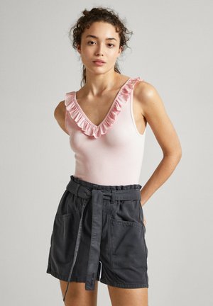 Top sin mangas rosa con escote con volantes y pantalones cortos oscuros con cinturón en gris con bolsillos laterales, ajuste relajado y textura de tela suave.