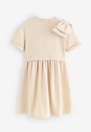 Helles beige Kleid mit kurzen Ärmeln, geripptem Ausschnitt und einem gerafften Rock. Verfügt über eine Schleifenakzent am rechten Schulter. Glatte Textur.