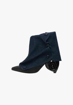 Botín de tobillo de mezclilla azul marino con un diseño estructurado, punta negra afilada y un exclusivo tacón en espiral. Presenta tres botones oscuros en el lateral.