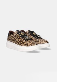 Zapatillas con estampado de leopardo y detalles en negro, con cordones planos y un adorno decorativo en la puntera. Cuentan con una suela de goma blanca gruesa.