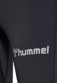 Zwart wetsuitmateriaal met een gladde textuur; voorzien van een zilveren "hummel" logo langs de zijkant en zichtbare stiksels.