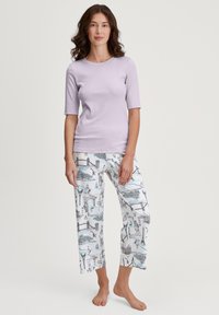 Lila kortemouwen top gecombineerd met witte pyjamabroek met zwarte contouren van herkenningspunten en kleurrijke accenten. Zachte, casual stof.
