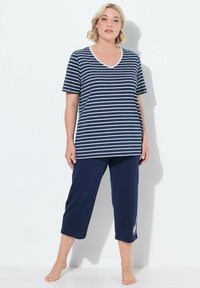 Top blu navy a righe con maniche corte e scollatura a V abbinato a pantaloni corti blu navy a tinta unita con un dettaglio di ricamo floreale sulla gamba.