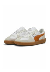 Hvide sneakers lavet af ruskind og læder, med en orange side-stribe, struktureret gummisål og klassisk snørelukning.