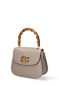 Borsa in pelle beige con forma arrotondata, manico in bambù, hardware dorato e chiusura a pattina, caratterizzata da linee pulite e dettagli minimi.