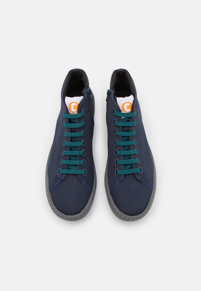 Marineblå høj-top sneakers med grønne snøre, grå såler og orange logo på hvid tunge, med en glat stofoverdel og syninger som detaljer.