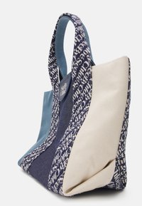 Niebieska, granatowa i beżowa torba wielokrotnego użytku z płótna, z szerokimi uchwytami oraz powtarzającym się wzorem tekstu "SeeByChloe" na bokach i uchwytach.