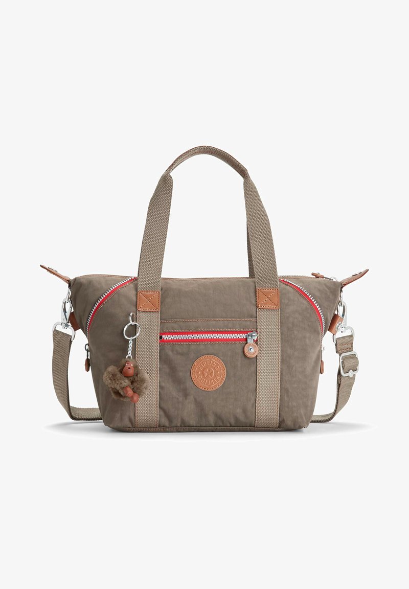Beige canvas bag with red zip, leather accents, dual handles, detachable strap, and a keychain monkey charm. Circular logo on front.