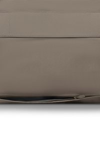 Close-up van taupekleurige stof met gedetailleerd stiksel en een gedeeltelijk open ritssluiting aan de onderrand.