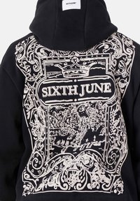 Sudadera negra con una gran gráfica blanca en la parte posterior que presenta diseños intrincados, incluidos las palabras "SIXTH JUNE" y una ilustración detallada de un paisaje urbano.