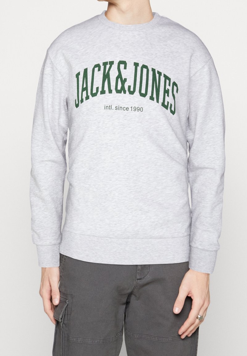 Szara bluza wykonana z miękkiego materiału, z zielonym logo "JACK&JONES" oraz napisem "intl. since 1990". Długie rękawy i ściągacze.