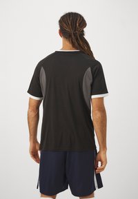 Black athletic shirt with gray side panels and white trim, short sleeves, paired with navy shorts, visible stitching, and relaxed fit.
