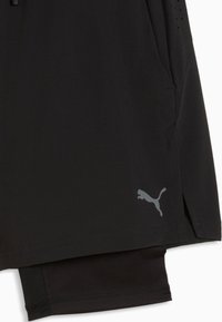 Μαύρο αθλητικό σορτς με ενσωματωμένη συμπιεστική στρώση και ανακλαστικό λογότυπο Puma κοντά στο τελείωμα στην εξωτερική στρώση.