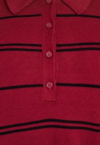 Rode polo shirt met een geribbelde textuur, een kraag, vijf knopen en horizontale zwarte strepen over de borst.