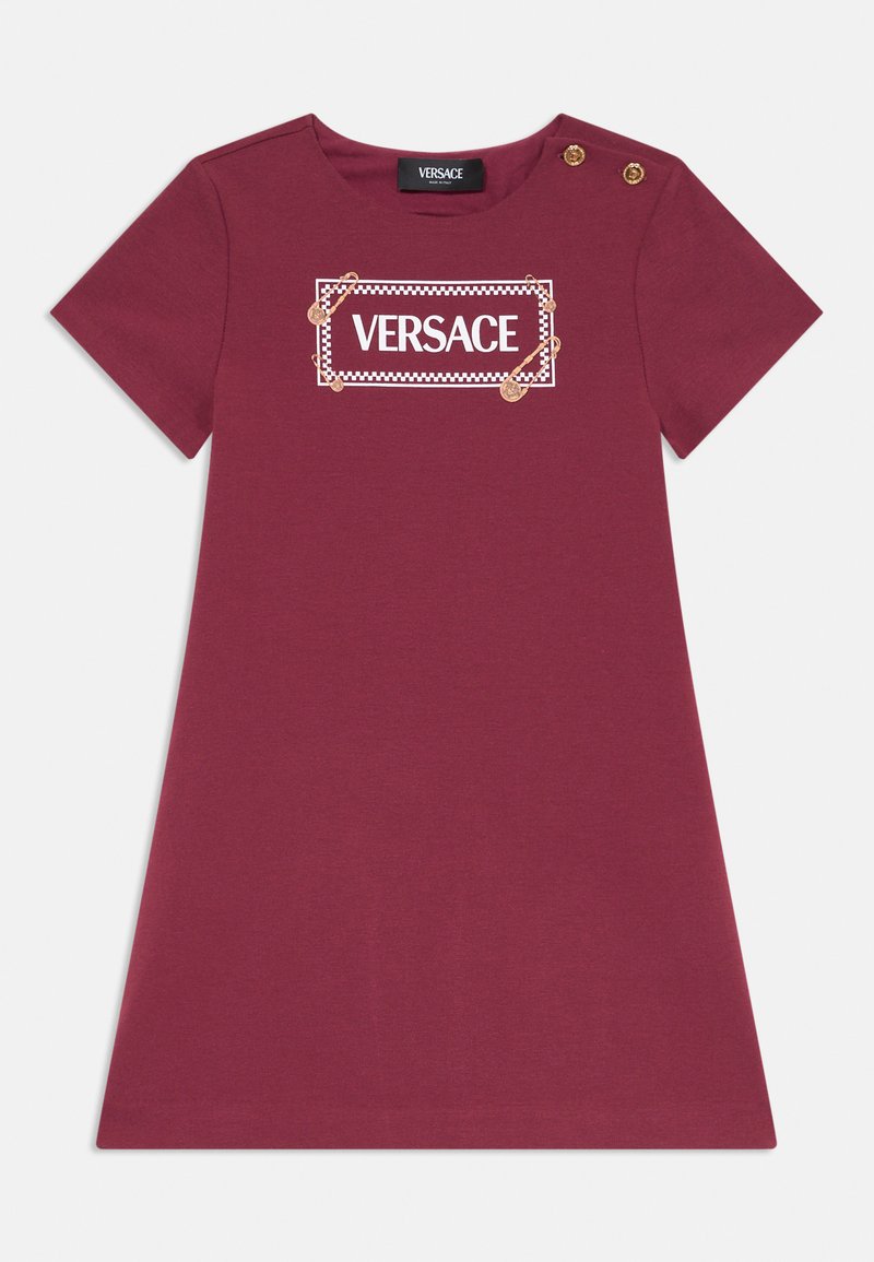 Bordo kleita ar īsām piedurknēm, apaļu dekoltē un zelta pogu akcentiem uz pleca. Uz kleitas ir balts Versace logotipa prints.